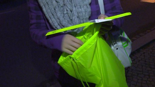 Policisté rozdávají lidem reflexní pásky.