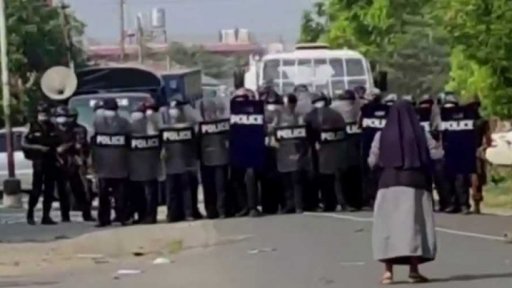 Jeptiška klečící před policejním kordonem